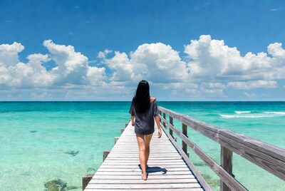 Woman walking on pier over turquoise ocean