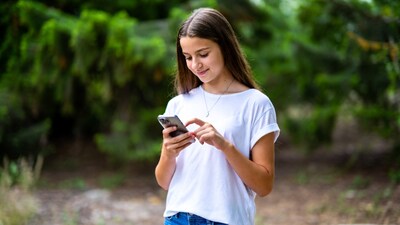 Teen girl using phone in forest