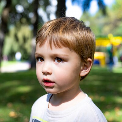 Blond boy looking sideways in park