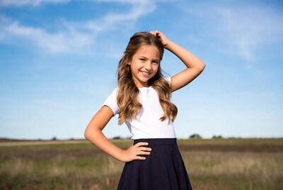 Smiling girl hand on head in field