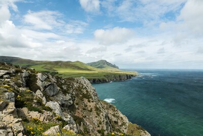 Cliff edge overlooking green hills and ocean