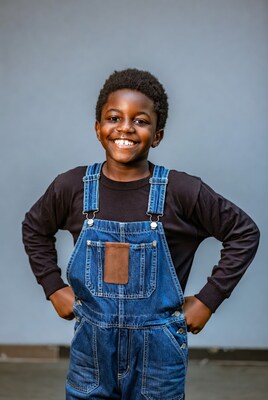 African-American boy in blue overalls smiling