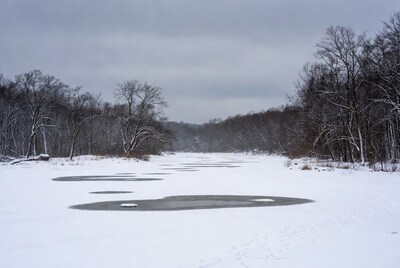 Frozen River with Ice Patches in Snowy Woods