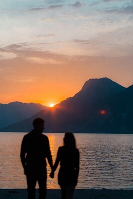 Couple holding hands at sunset lake