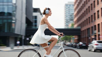 Woman biking in white dress with headphones