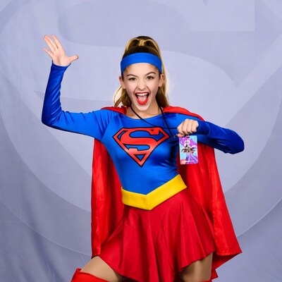 Girl in Supergirl costume waving