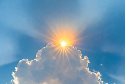 Sun rays through clouds in blue sky