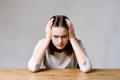 Young woman holding head stressed at table