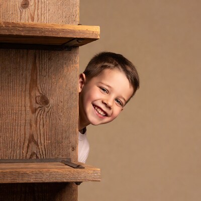 Boy peeking from wooden bookshelf