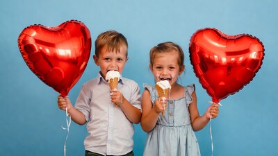 Boy and girl eating ice cream with heart balloons