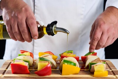 Chef pouring oil on veggie skewers