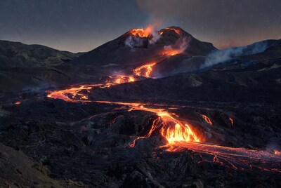 Volcano erupting with lava flow at night