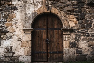 Wooden arched door in stone wall