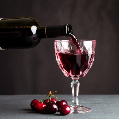 Red wine pouring into glass with cherries