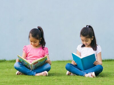 Asian girls reading books on grass
