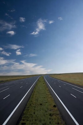 Empty road curving through grassy fields