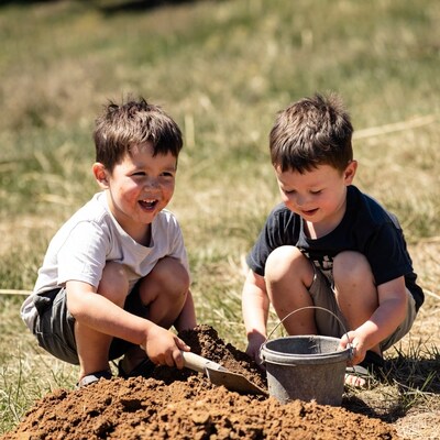 Two boys digging in dirt with shovel
