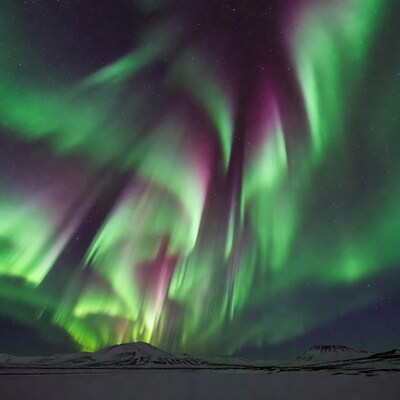 Vibrant Northern Lights over Snowy Mountains