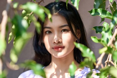 Asian woman peeking through green leaves