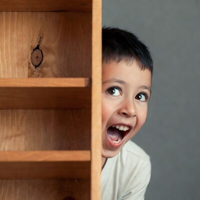 Boy peeking from wooden bookshelf