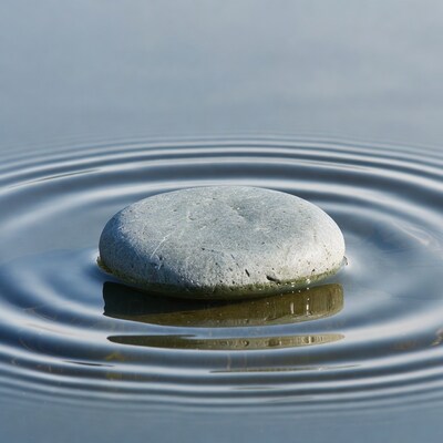 Gray pebble creating ripples in water