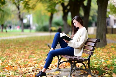 Woman reading book on park bench