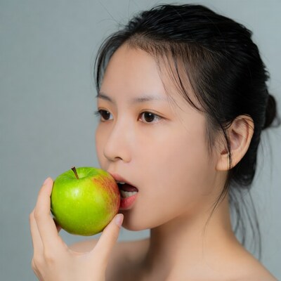 Asian woman biting green apple