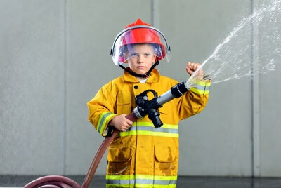 Boy firefighter holding hose
