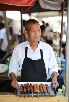 Asian man holding grilled skewers