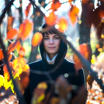 Woman in hoodie among autumn leaves