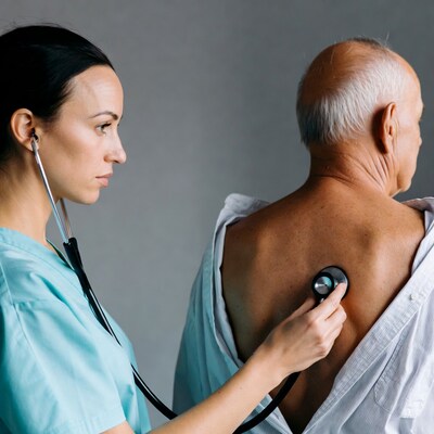 Nurse listening to elderly man's back