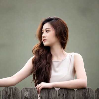 Asian woman leaning on wooden fence