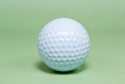 White golf ball on green background
