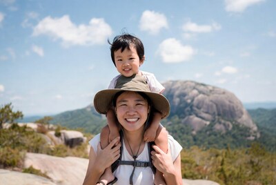 Asian mother carrying baby on shoulders hiking