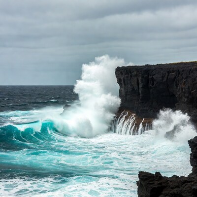 Waves crashing against black cliffs