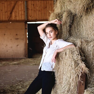 Young woman leaning on hay bales
