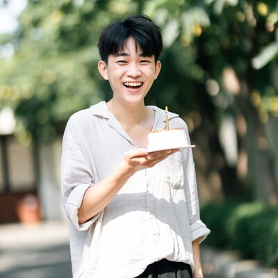 Asian boy holding birthday cake outdoors