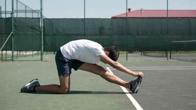 Asian man stretching on tennis court