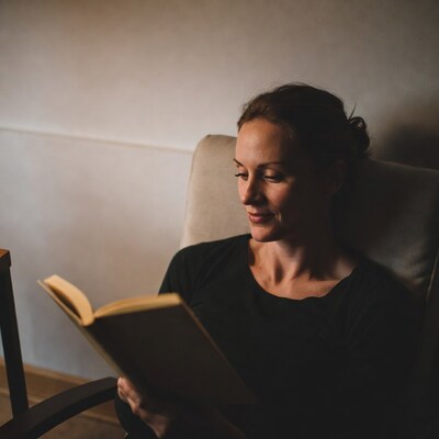 Woman reading book in armchair