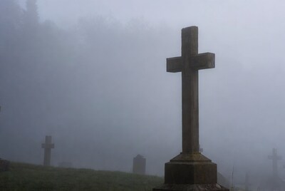 Wooden cross in foggy cemetery
