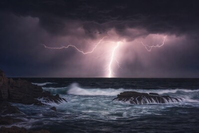 Lightning striking over ocean rocks