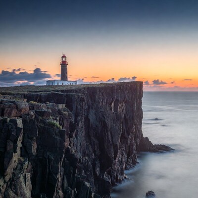 Lighthouse on cliff at sunset