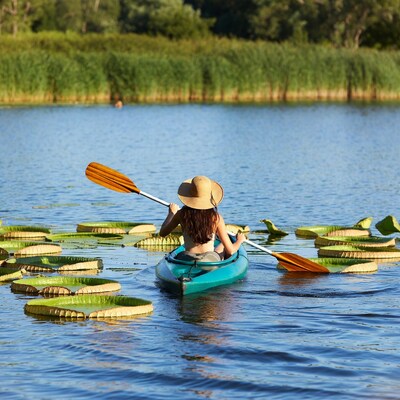 Woman kayaking through water lilies