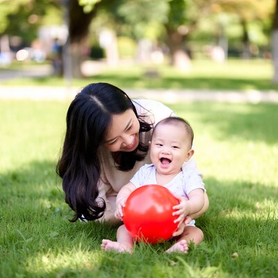 Asian mother and baby playing with red ball
