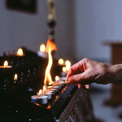 Hand lighting candle in church