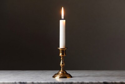Lit white candle on brass candlestick