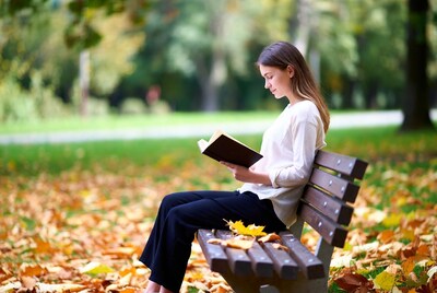 Woman reading book on park bench