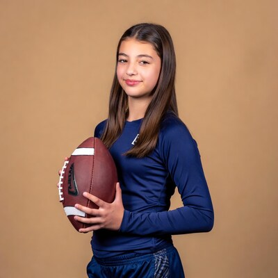 Girl holding football in blue uniform