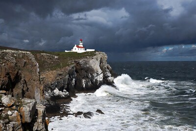 White lighthouse on cliff stormy ocean