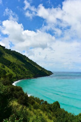 Tropical green hills meeting turquoise ocean